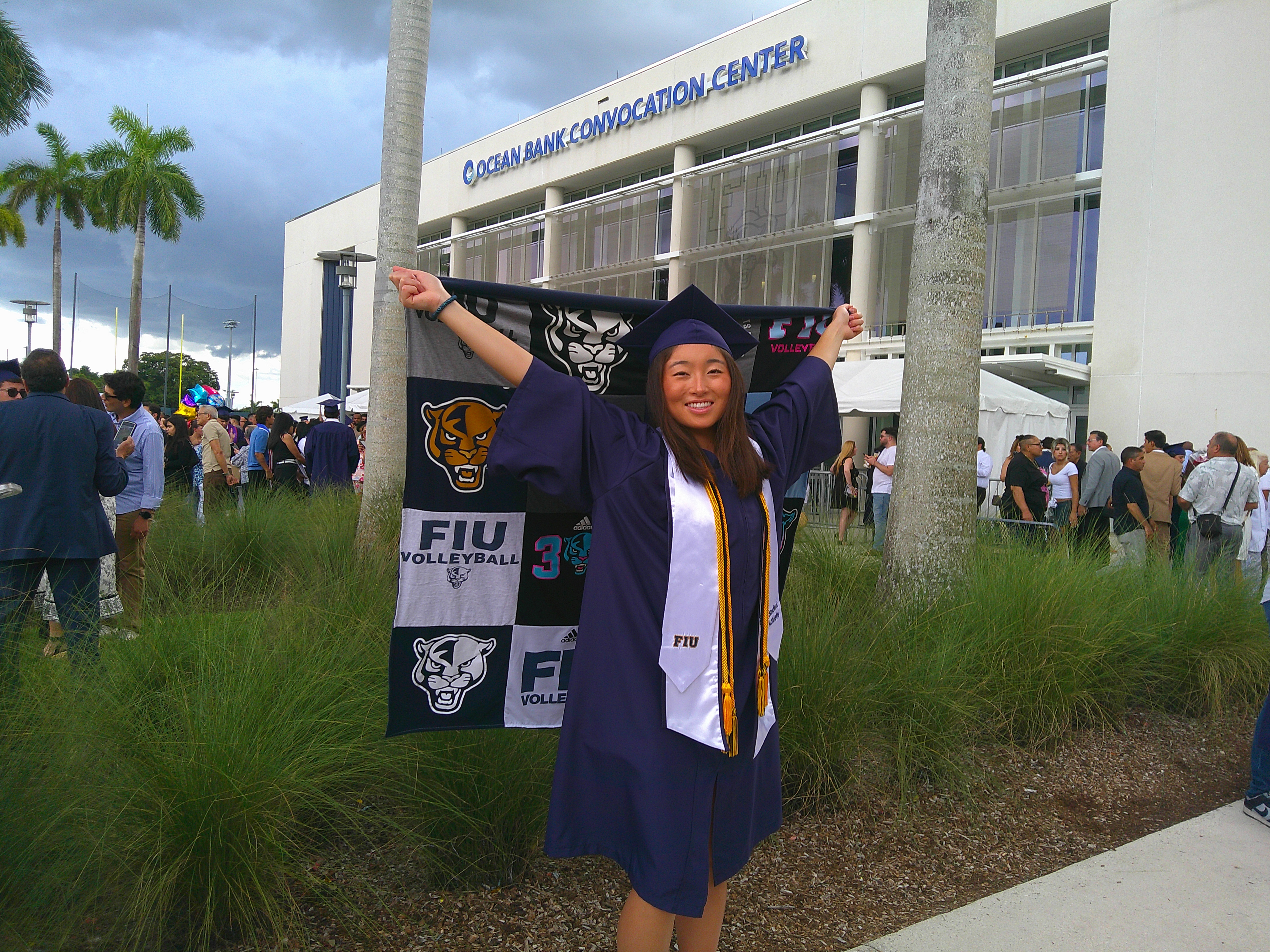 High school graduate in cap and gown celebrating graduation with family