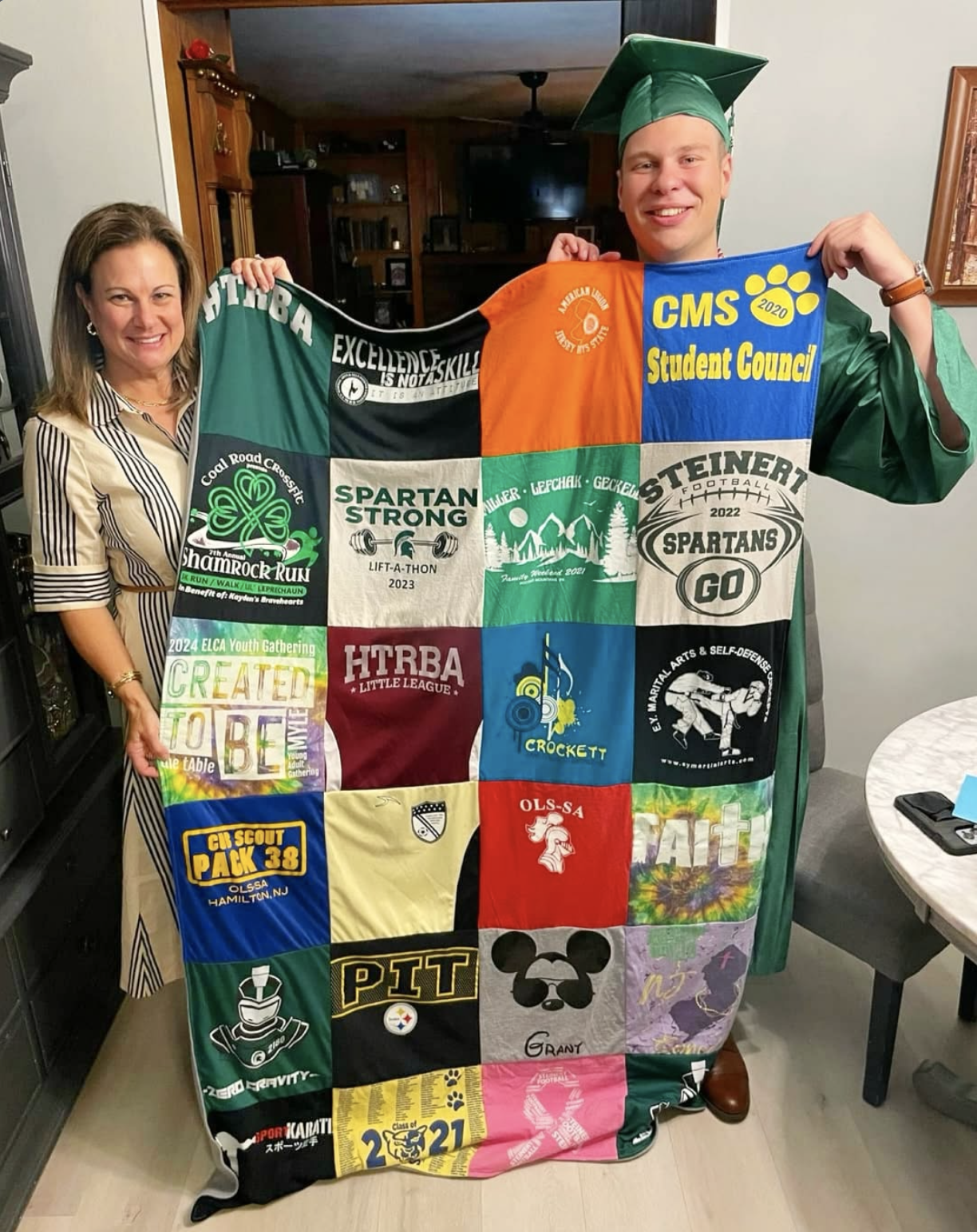 Mom and son at high school graduation holding large custom t-shirt memory quilt — Project Repat